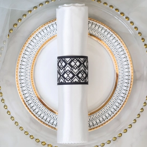 Close-up of laser-cut black geometric napkin ring on a white cloth for wedding decor
