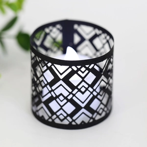 Detail of a black geometric laser-cut paper lampshade with a warm LED electronic candle light