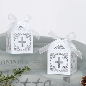 White laser-cut cross favor boxes with elegant scroll patterns and organza bows