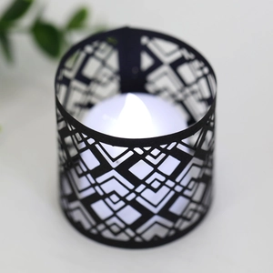 Macro shot of black geometric cutout candle holder with warm white LED electronic candle
