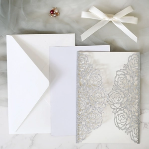 Detailed laser-cut silver glitter rose invitation with white satin ribbon and pearl brooch