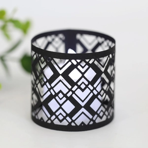 Detail of black geometric hollow candle holder with warm LED light shadows