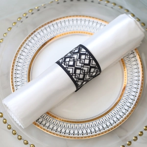 Close-up of black laser-cut geometric napkin ring with diamond pattern on white fabric