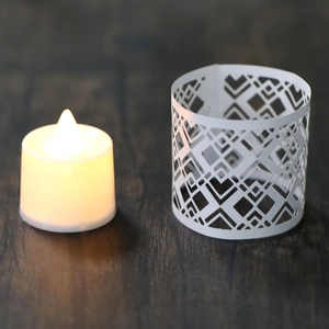 Detailed view of white hollow paper lampshade with warm LED candle on wood table