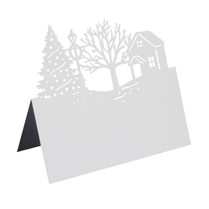 Laser-cut white pearlescent paper table card with intricate Christmas tree and house patterns