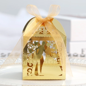 Close-up of golden laser-cut wedding favor box featuring bride and groom silhouette