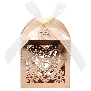 Detailed laser-cut heart and floral pattern on rose gold favor box with ribbon
