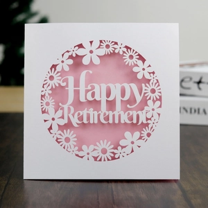Close-up of laser-cut Happy Retirement card with white lace and pink insert on wood