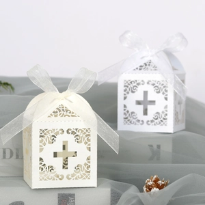 Elegant laser-cut cross favor boxes in cream and white with silk ribbon and floral patterns