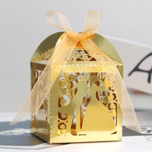 Close-up of golden laser-cut wedding favor box with silhouette design and ribbon bow