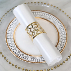 Detail of a golden laser-cut geometric napkin ring on a white satin napkin for wedding