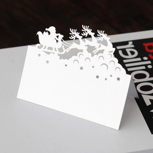 Macro detail of laser-cut white pearl paper place card with Santa and reindeer