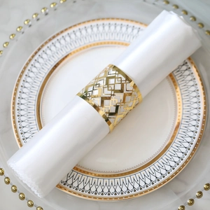 Close-up of golden geometric laser-cut napkin ring on a white silk napkin and plate
