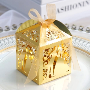 Detail view of gold laser-cut wedding favor box with heart silhouettes and ribbon bow