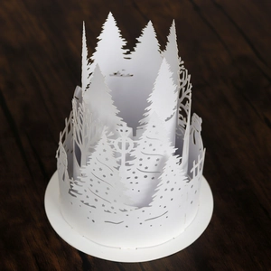 Detail of 3D cutout paper lamp shade featuring intricate winter forest silhouettes