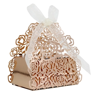 Detailed laser-cut rose pattern on rose gold wedding favor box with white silk ribbon