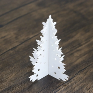 Macro detail of laser-cut white paper Christmas tree decoration on wood background