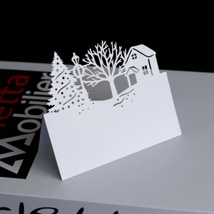Detailed laser-cut Christmas tree and house silhouette on white pearlescent paper card