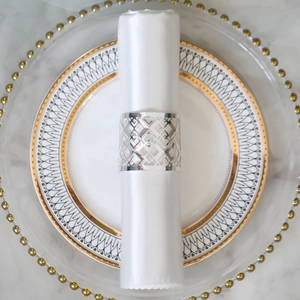 Detail of silver geometric cut-out napkin ring on a white napkin for wedding table setting