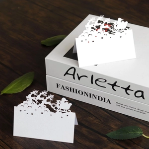 Detailed laser cut white Christmas table cards with reindeer and Santa Claus motifs