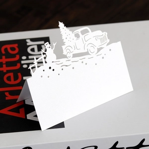 Detail of laser cut white paper place cards with snowman and Christmas tree motifs