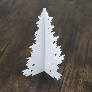 Detailed view of white laser-cut paper Christmas tree with circular hollow cutouts