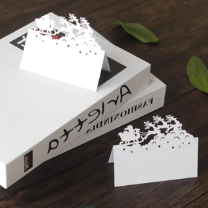 Laser-cut Christmas table cards featuring Santa and reindeer silhouette on white cardstock