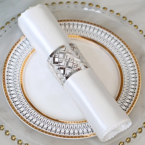 Detailed macro view of silver hollow diamond pattern metal napkin ring on a white napkin