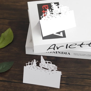 Laser-cut Christmas table cards featuring snowman and tree motifs on white cardstock