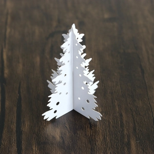 Close-up of a white 3D paper Christmas tree with laser-cut hollow dots for table decor