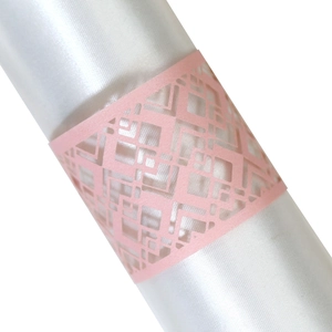 Detail of pink laser-cut geometric napkin ring on white satin fabric for wedding decor