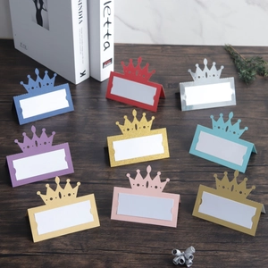 Close-up of laser-cut crown place cards in nine colors on a wooden surface