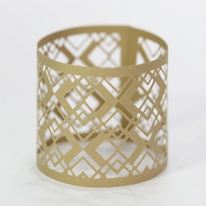 Detail of golden geometric cutout LED candle sleeve with intricate laser-cut patterns