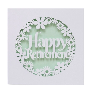 Close-up of laser-cut white card with Happy Retirement text and floral patterns