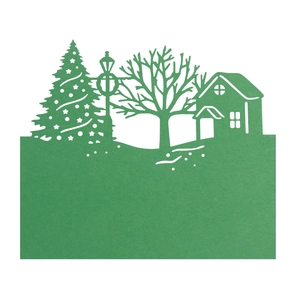 Macro detail of laser-cut green paper Christmas house and tree silhouette table card