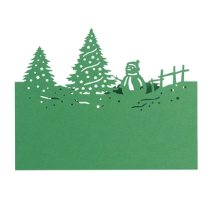 Detail of dark green laser-cut Christmas card featuring snowman and holiday pine trees