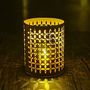 Hollow flower geometric metal candle holder with warm yellow light on wood table