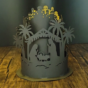 Close-up of laser-cut nativity scene lampshade with warm light on wooden surface