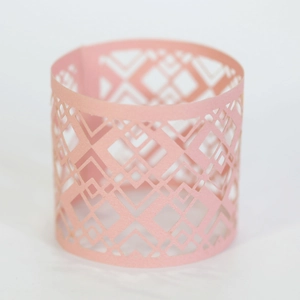 Detail of pink laser-cut paper napkin ring featuring a geometric diamond hollow pattern