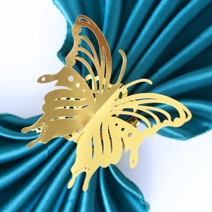 Laser-cut hollow butterfly napkin ring in gold finish on elegant blue fabric