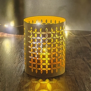 Cylindrical hollow paper lampshade with laser-cut geometric patterns and warm glowing light