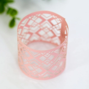 Macro view of laser-cut pink napkin ring with geometric diamond hollow pattern