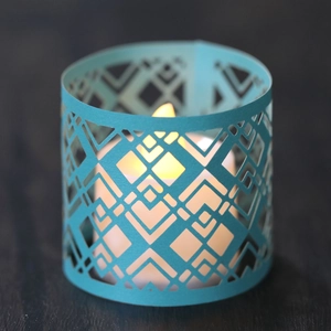 Blue hollow paper candle shade with geometric laser cut patterns and warm LED light