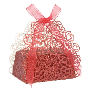 Macro detail of laser-cut rose patterns on a red glitter wedding favor box with ribbon