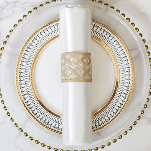 Detailed close-up of laser-cut gold napkin ring with geometric patterns on a white cloth