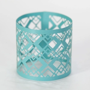 Macro shot of light blue laser-cut hollow geometric paper sleeve for LED candle lights