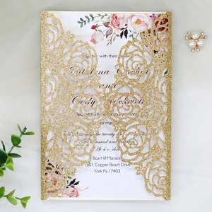 Detail of laser-cut rose pattern on gold glitter wedding invitation with floral inner card