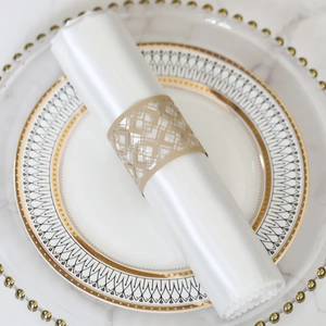 Detail of laser-cut gold napkin ring with geometric hollow pattern on a satin napkin