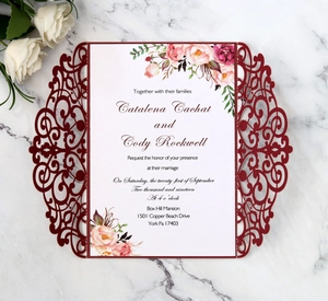 Close-up of laser-cut burgundy wedding invitation with elegant floral inner card