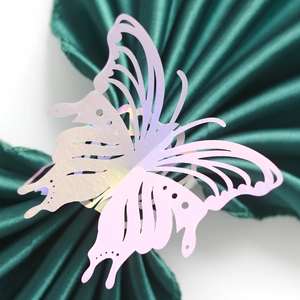 Macro detail of laser-cut butterfly napkin ring with iridescent finish on green satin